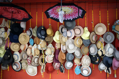 Multiple hats and umbrellas hung on wall for sale at petaling street market in kuala lumpur