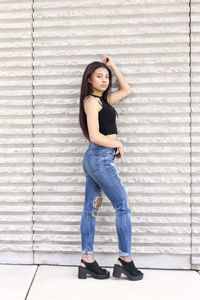 Portrait of a beautiful young woman standing against wall