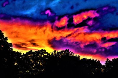 Low angle view of silhouette trees against dramatic sky