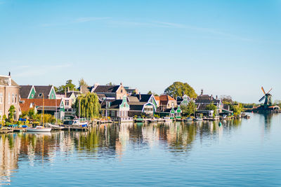 Sailboats in river by buildings against sky