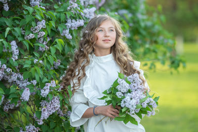 Portrait of beautiful woman standing by flowering plants