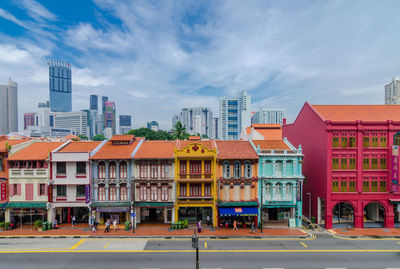 Road by colorful buildings against sky in city