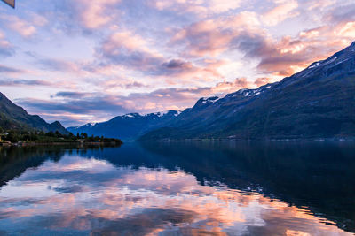 Scenic view of lake by mountains against sky during sunset