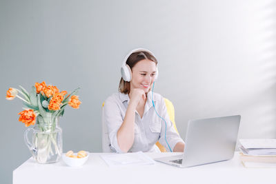 Middle age woman in headphones sitting at desktop working on laptop, computer. video school class 