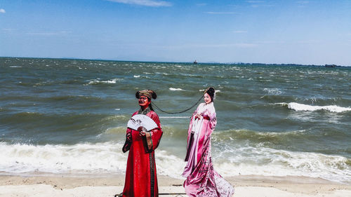 Women standing at beach against sky