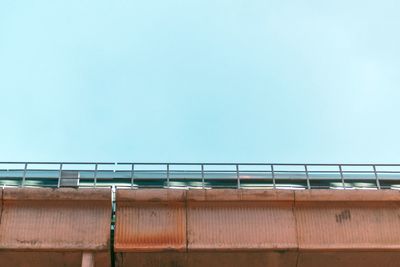 Low angle view of railing against clear blue sky