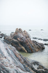 Rock formation on beach against sky