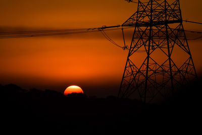 Silhouette electricity pylon against sky during sunset