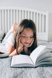 Girl looking away while sitting on bed