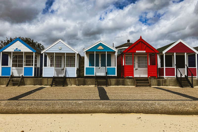 Houses on beach by buildings against sky