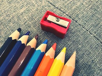 High angle view of colored pencils with sharpener on table