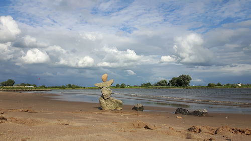 View of calm beach against cloudy sky