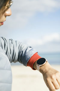 Shot of happy latin woman dressed in anorak checks fitness results on smartwatch  healthy lifestyle