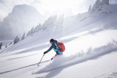 Mid adult woman skiing on snowcapped mountain during sunny day