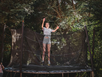 A beautiful slender caucasian teenage girl in shorts and a blouse jumps on a trampoline