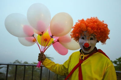 Low angle view of person holding balloons against sky