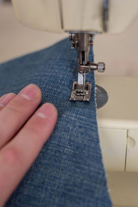 Close up of a person sewing blue jeans on a sewing machine