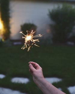 Close-up of hand holding sparkler against sky