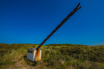 Windmill on field against clear blue sky