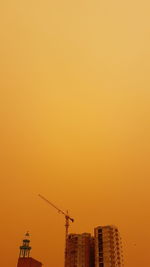 Low angle view of silhouette cranes against sky during sunset