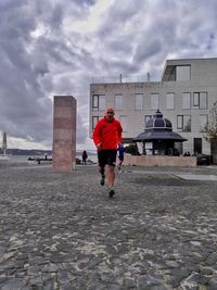 Rear view of man on beach against sky in city