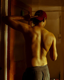 Rear view of shirtless man standing at home