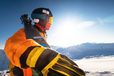 Skier in the winter mountains against the backdrop of a sunny sky, wide angle from below, a man