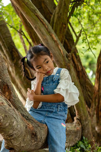 Thoughtful cute girl sitting on tree