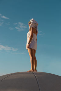 Full length of woman standing on road against sky