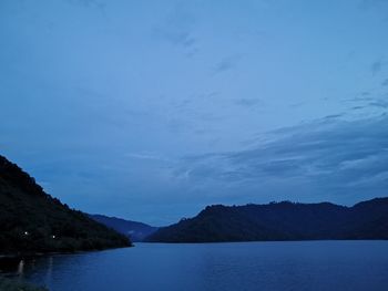 Scenic view of lake and mountains against blue sky