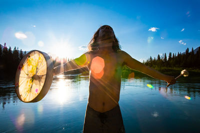 Rear view of woman standing by lake against sky