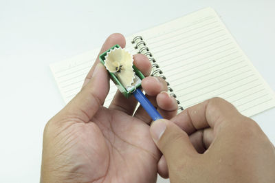 Close-up of hand holding book against white background