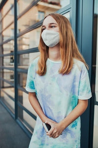 Girl wearing mask looking away while standing outdoors