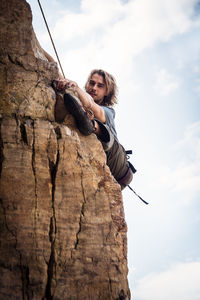 Low angle view of man on rock against sky