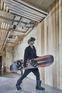 Mature businessman wearing vr glasses holding snowboard in modern office