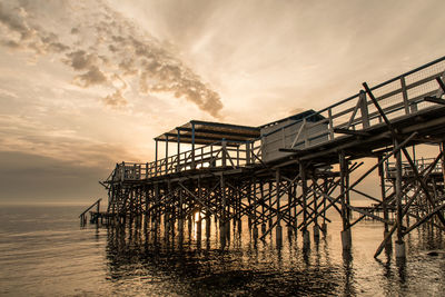 Pier over sea against sky during sunset