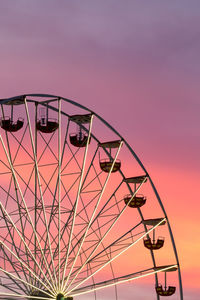 Low angle view of ferris wheel against sky during sunset