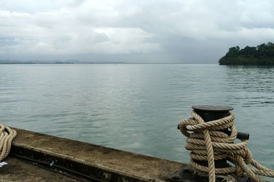 Pier on sea against cloudy sky
