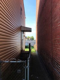 Railing in alley against blue sky