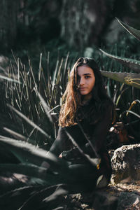 Portrait of young woman sitting amidst plants