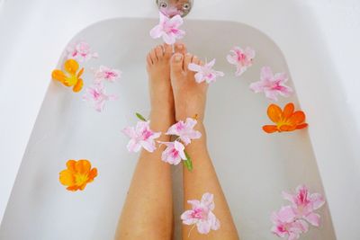 Low section of woman with flower in bathtub