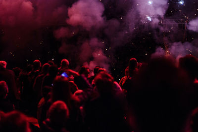 Crowd by smoke at music concert during night