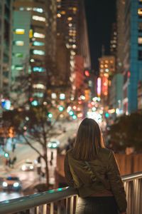 Rear view of woman on illuminated street at night