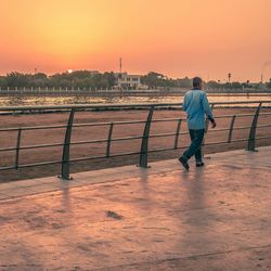 View of man walking on footpath during sunset