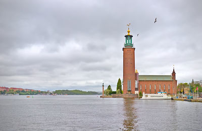 Lighthouse by sea against sky