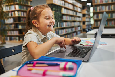 Student doing homework using laptop in after school club at school. back to school. happy student