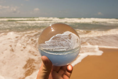 Midsection of person holding crystal ball on beach