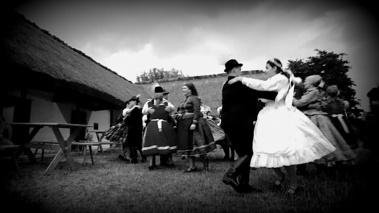 FRIENDS STANDING ON FIELD BY TRADITIONAL CLOTHING