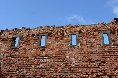 Low angle view of old brick wall against clear sky