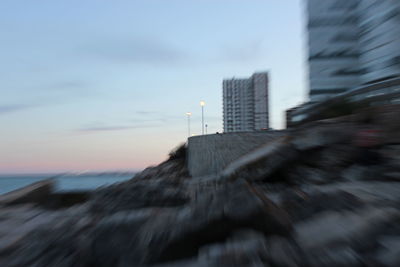 Blurred motion of building by sea against sky during sunset